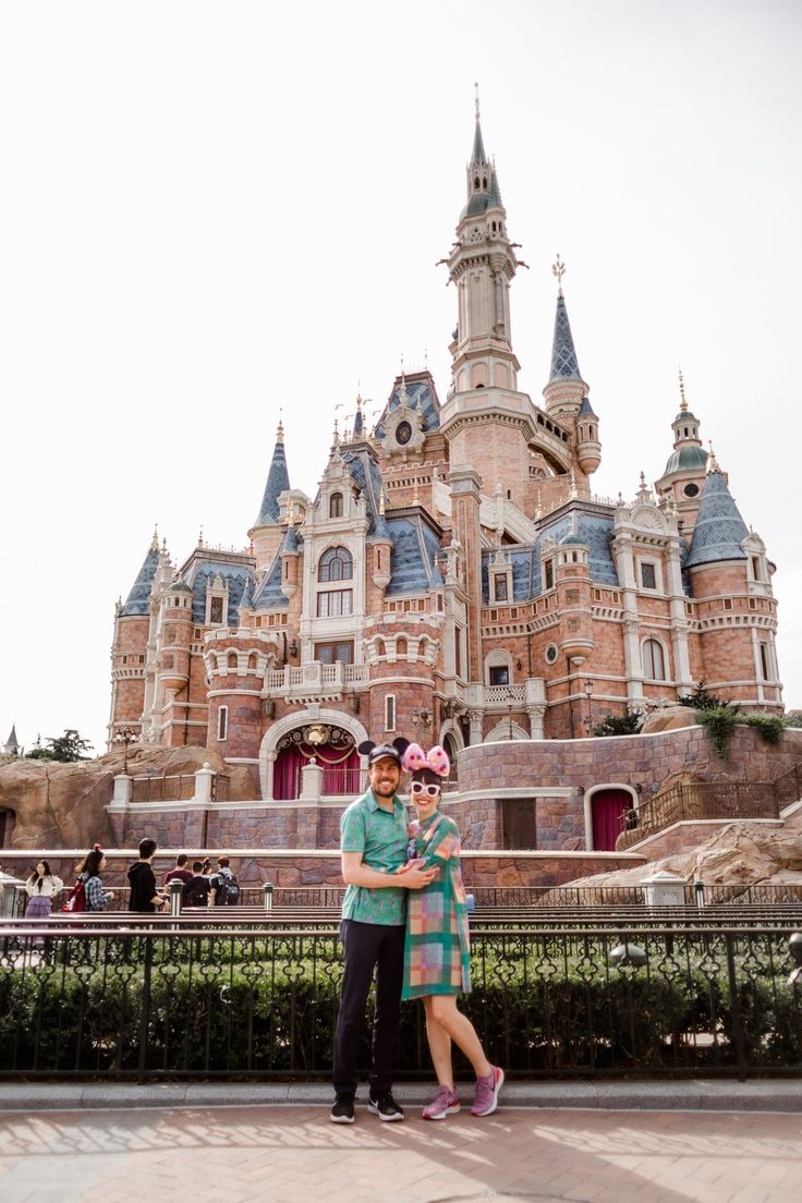 a man and woman standing in front of a castle