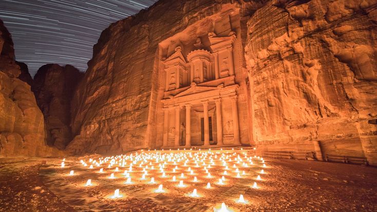 many lit candles are placed in the middle of a desert area with rocks and cliffs