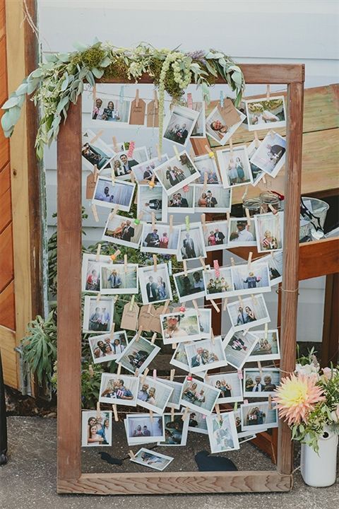 a wooden frame with photos attached to it and flowers on the table next to it