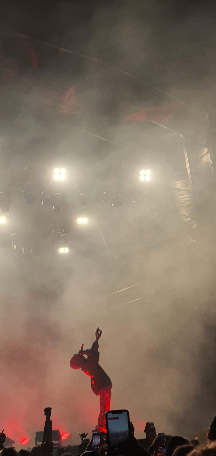 a man standing on top of a stage in front of a crowd at a concert