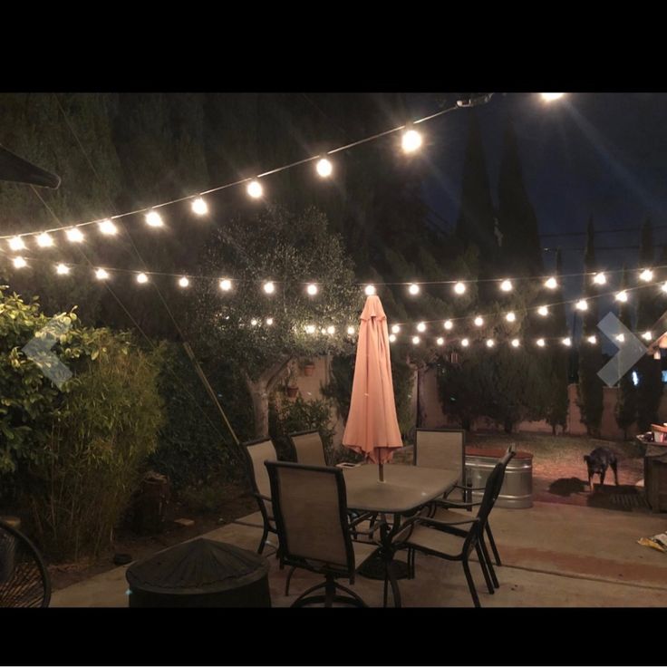 an outdoor dining area with patio furniture and string lights