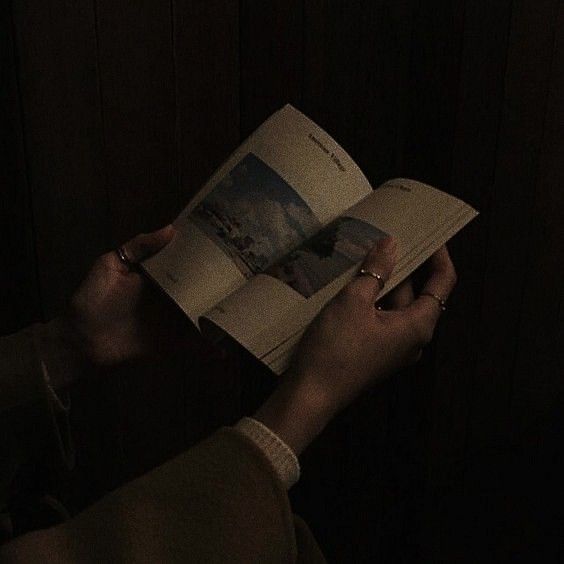 a person reading a book in the dark with their hand on top of an open book
