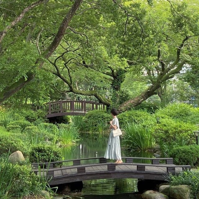 a woman standing on a bridge over a pond