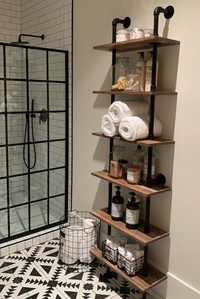 a black and white tiled bathroom with shelves on the wall next to a walk in shower