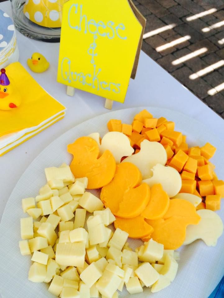 cheese and crackers on a white plate next to a yellow ducky place card