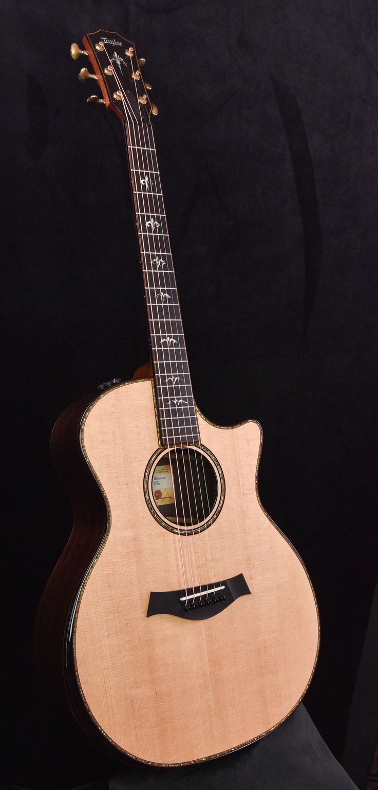 an acoustic guitar sitting on top of a black background