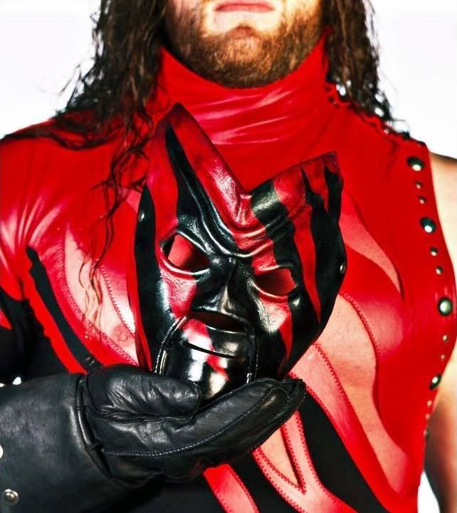 a man with long hair wearing a red and black leather outfit is holding his hands together