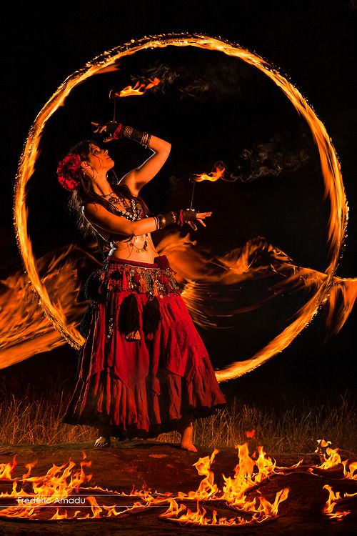 a woman is dancing with fire in the air