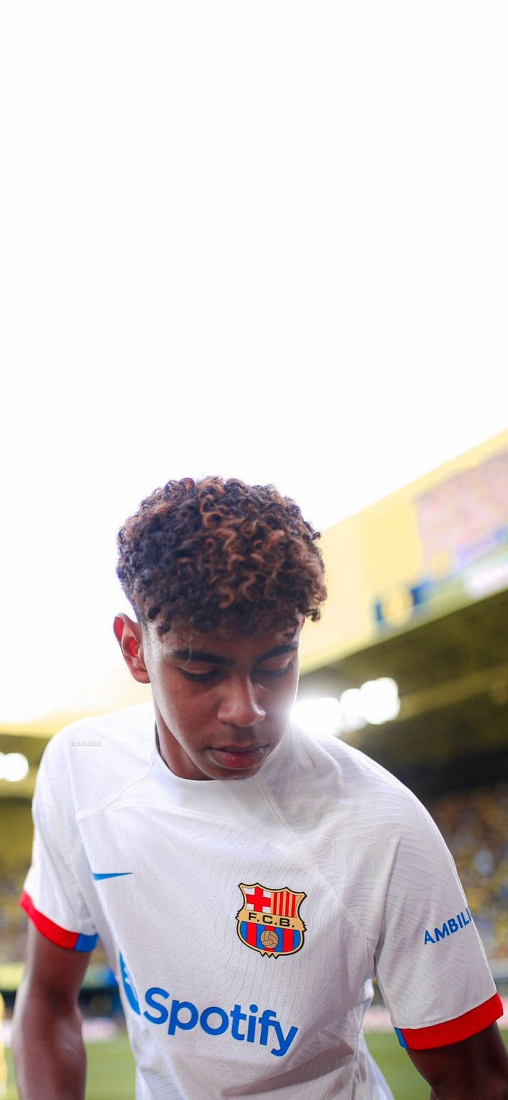 a young man standing on top of a soccer field wearing a white and red shirt