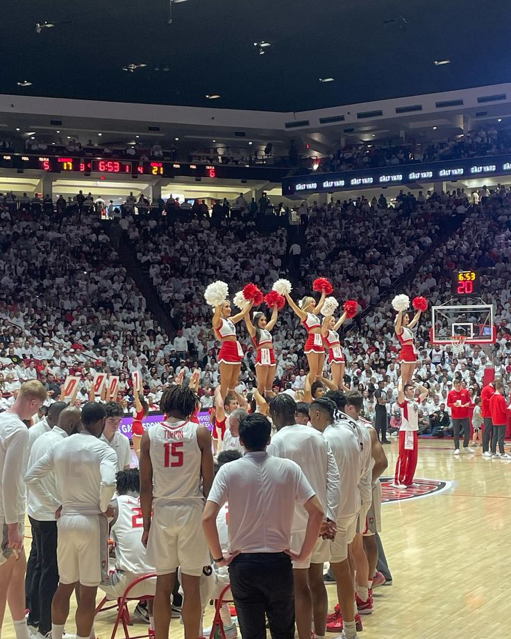 a group of cheerleaders standing on top of a basketball court in front of an audience