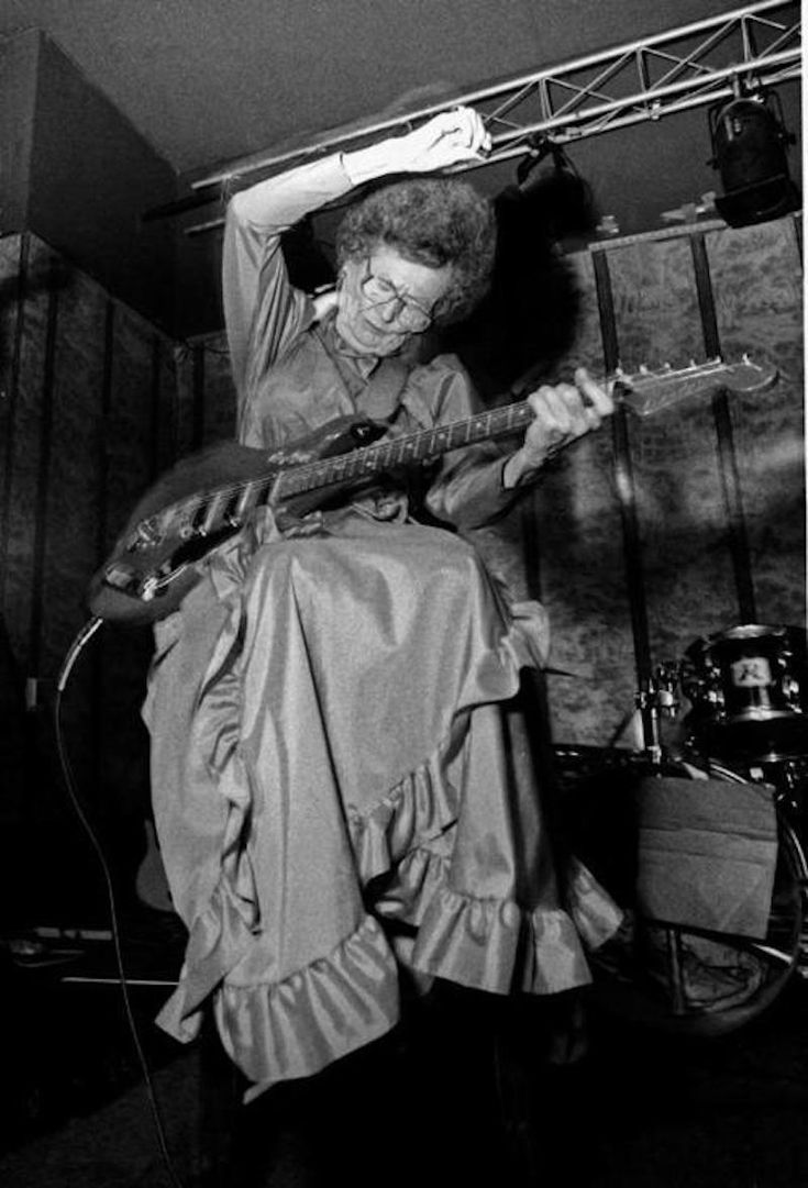 a black and white photo of a woman playing an electric guitar