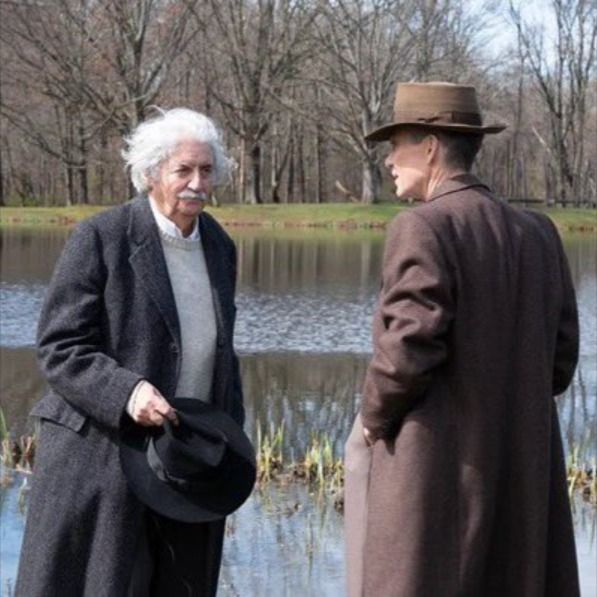 two men standing next to each other near water