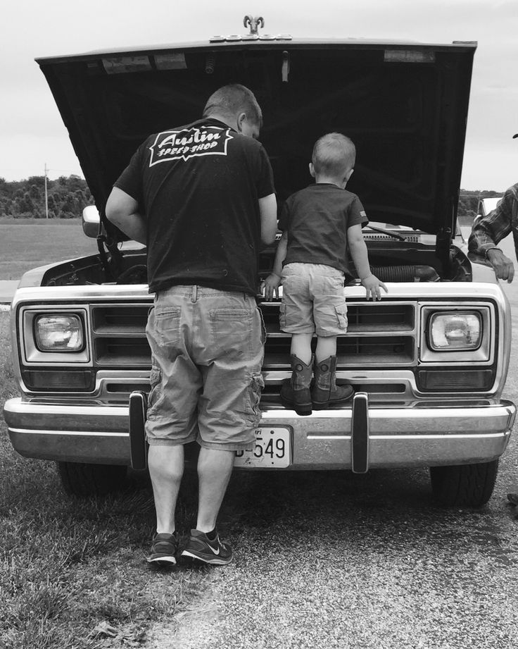 two men and a child are standing in the back of a truck with its hood open