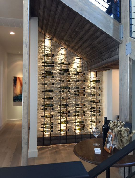 a wine cellar with lots of bottles on the wall next to a table and chairs