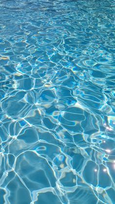 an empty swimming pool with blue water and sun reflecting off the surface on the water