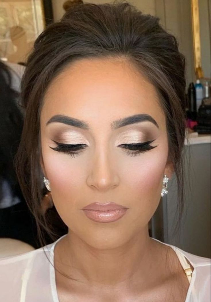 a woman with dark hair and makeup looks down at the camera while she has her eyes closed