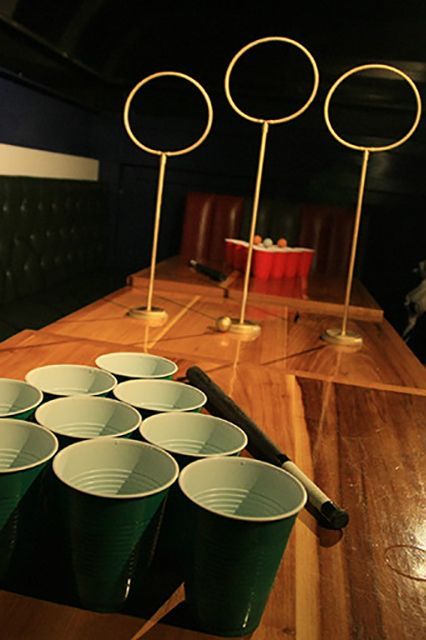 several cups are lined up on a table in a room with green leather booths and black walls