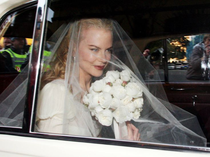 a woman in a car with a veil on her head and flowers in her hand