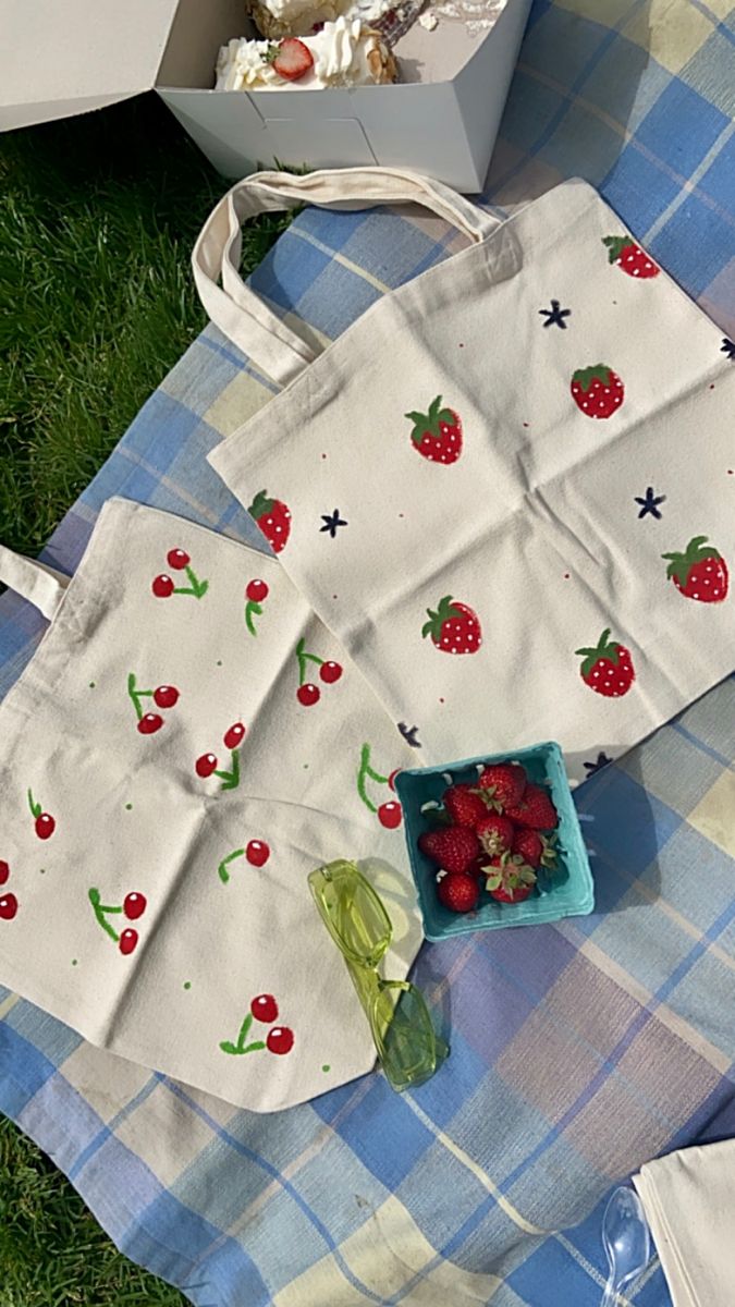 strawberries and other fruit are on the picnic blanket