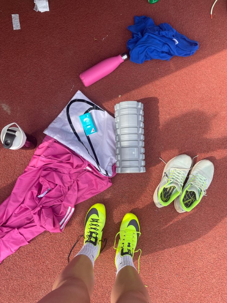 a person's feet are shown next to sports equipment and water bottles on the ground