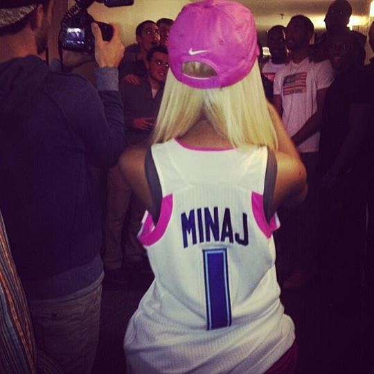 a woman with blonde hair wearing a white jersey and pink hat is taking a selfie