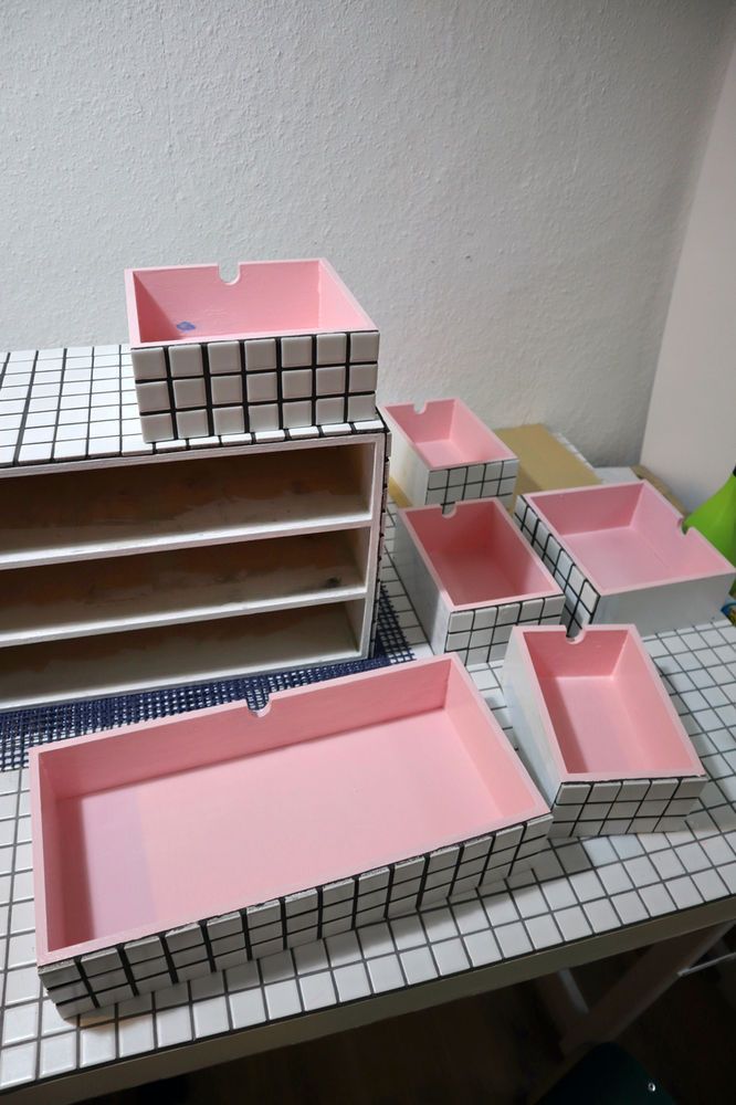 some pink trays are sitting on a table with white tiles and black grout