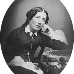 an old black and white photo of a woman sitting at a desk with her hand on her chin