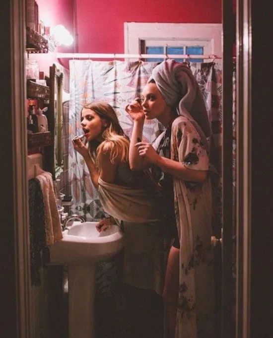 two women standing in front of a mirror brushing their teeth