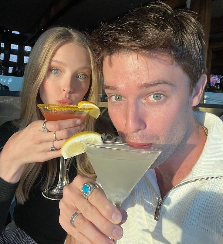 a man and woman are drinking martinis at a bar with lemon wedges in their mouths