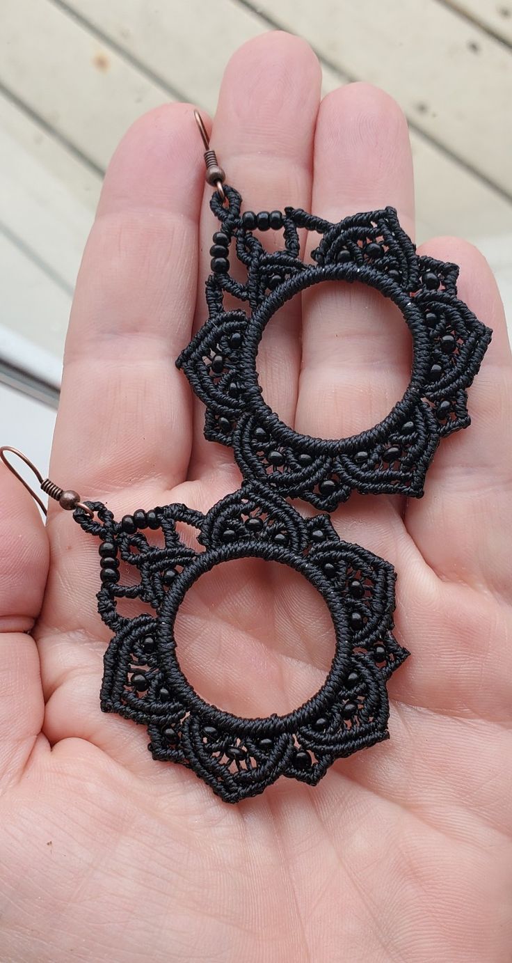 a pair of black earrings is being held in someone's hand