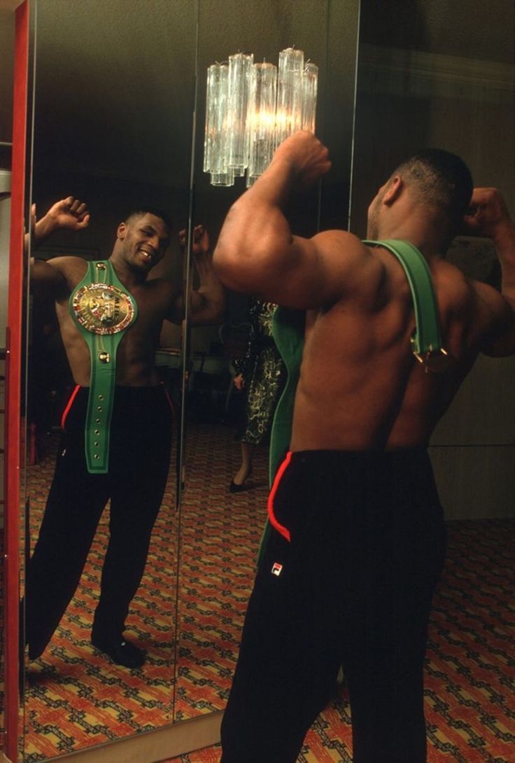 a man standing in front of a mirror taking a selfie with his arm up