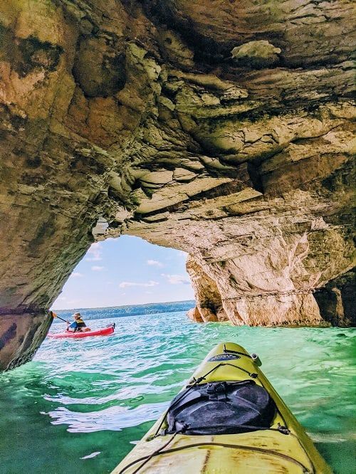 a person in a kayak looking out into the ocean from inside a cave on an island