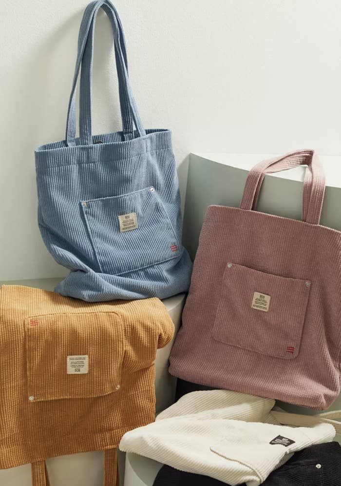 three bags sitting on top of each other next to a white wall and a blue bag