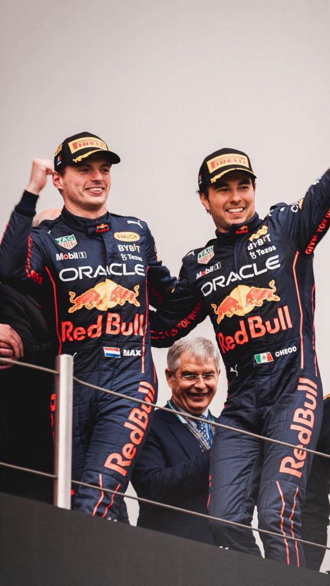 two men in racing uniforms standing on the side of a staircase with their hands up