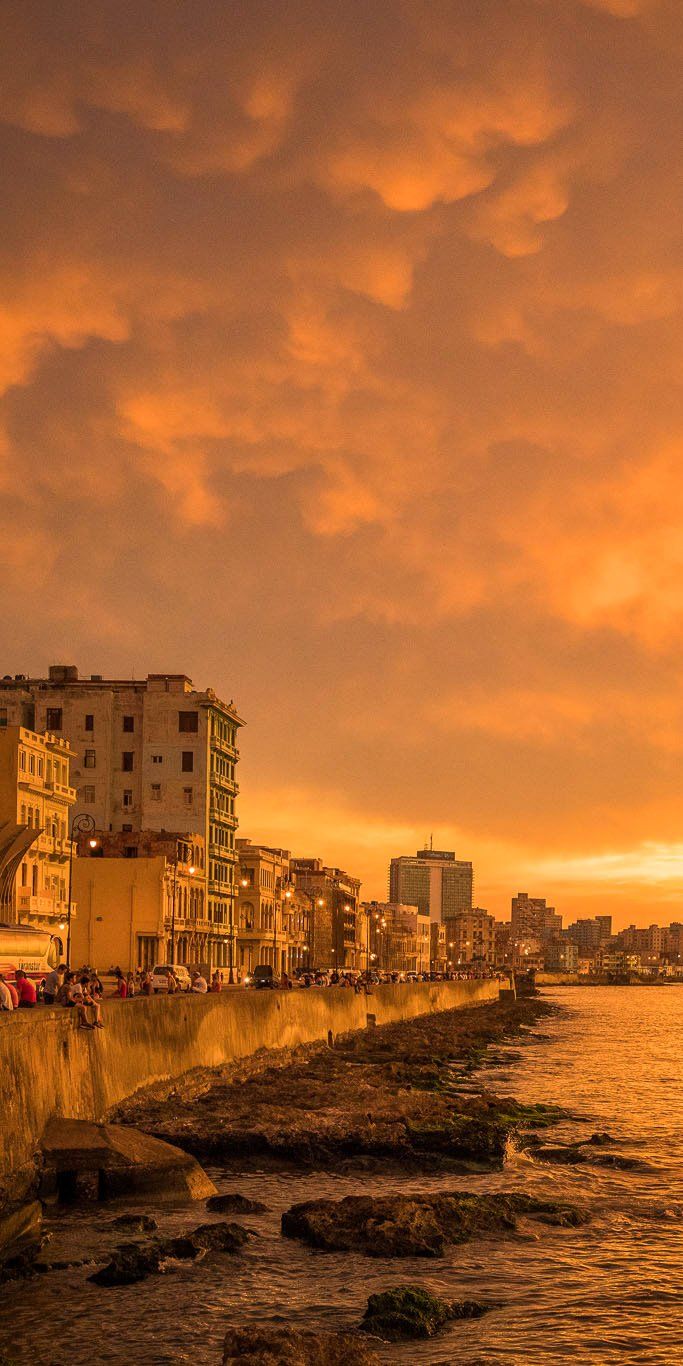 an orange sky over the ocean and buildings