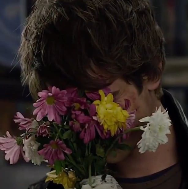 a man holding a bouquet of flowers in his face