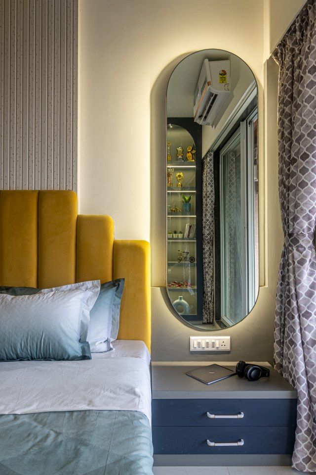 a bedroom with a large mirror above the bed and yellow headboard on the nightstand