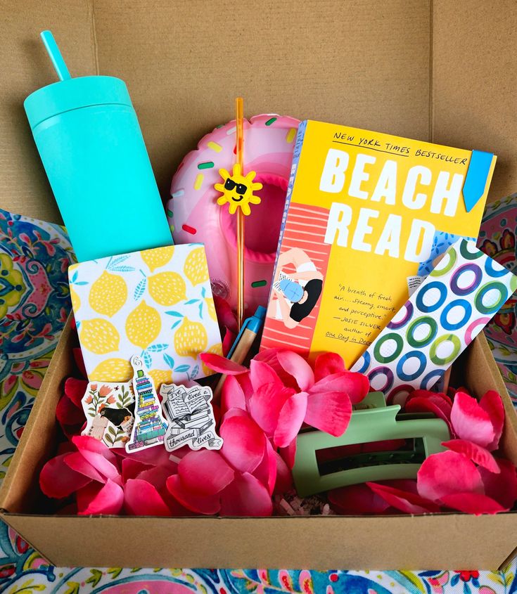 a box filled with lots of books and items on top of a bed covered in pink flowers