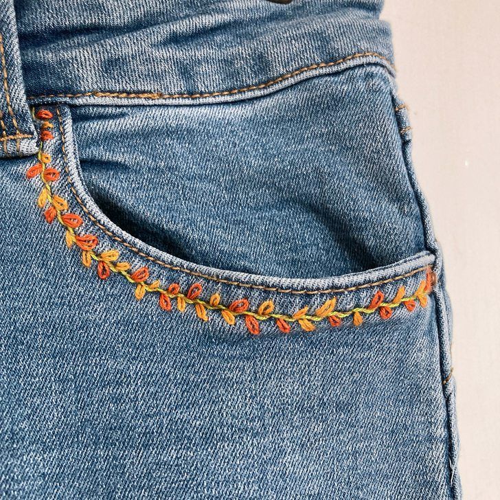 the back pocket of a pair of jeans with embroidered flowers on them, showing how to sew