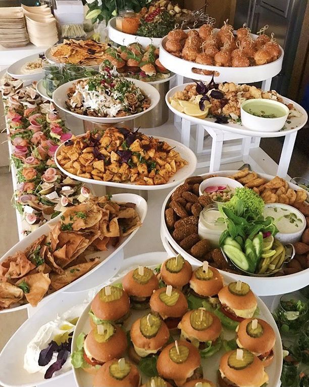 a table filled with lots of different types of food on top of white trays