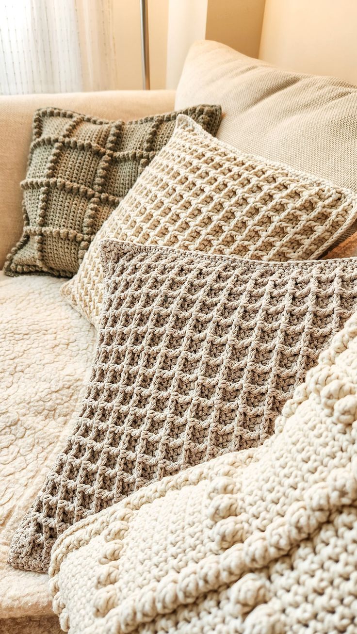 two crocheted pillows are sitting on a couch