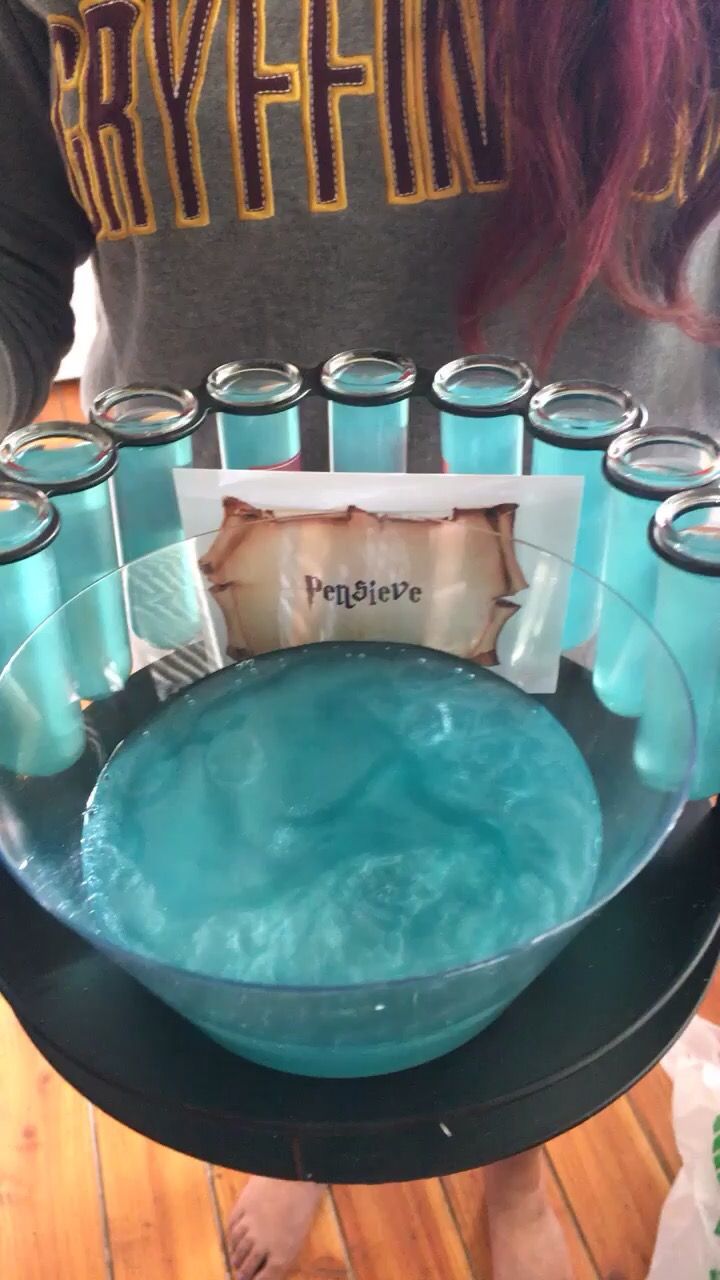 a woman is holding a tray with blue liquid in it and several empty glass jars