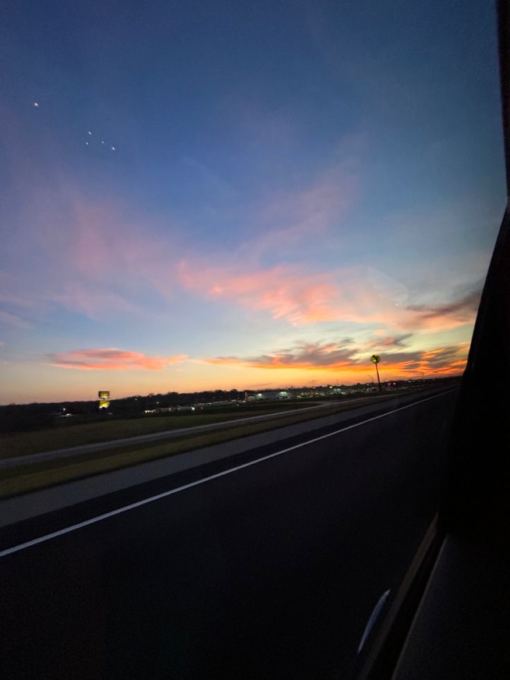 the sun is setting on an empty highway