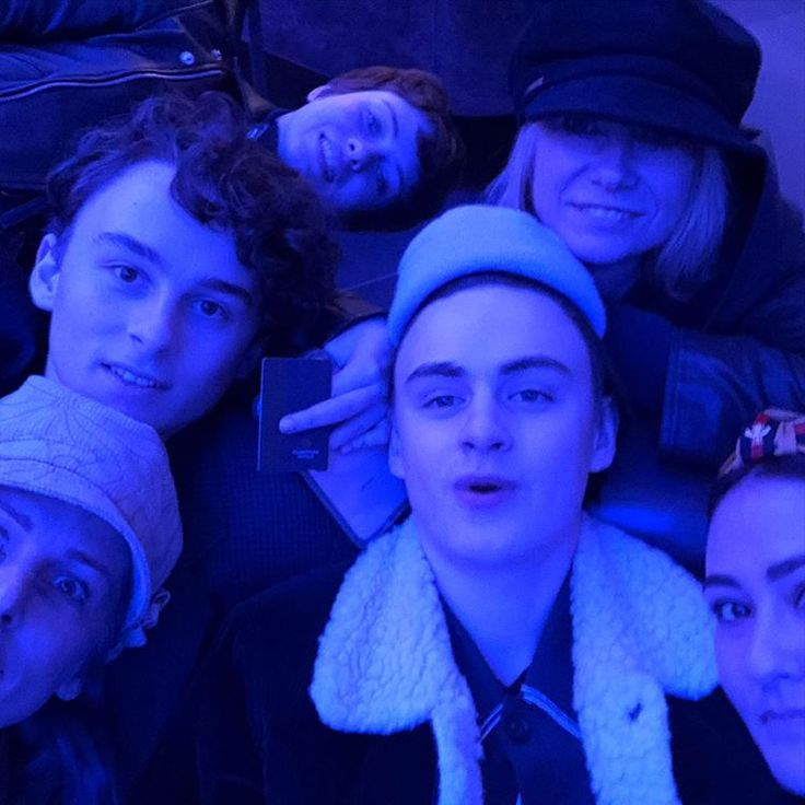 a group of young people posing for a photo in front of the camera, all wearing hats and scarves