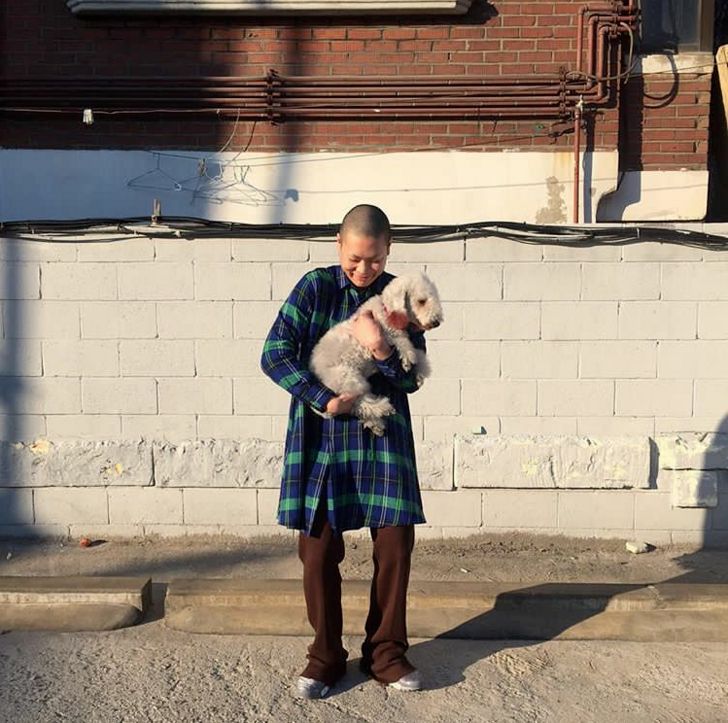 a young man holding a small white dog in his arms while standing on the sidewalk