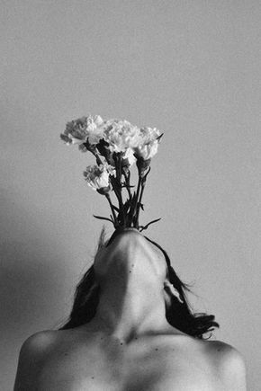 a black and white photo of a woman with flowers on her head