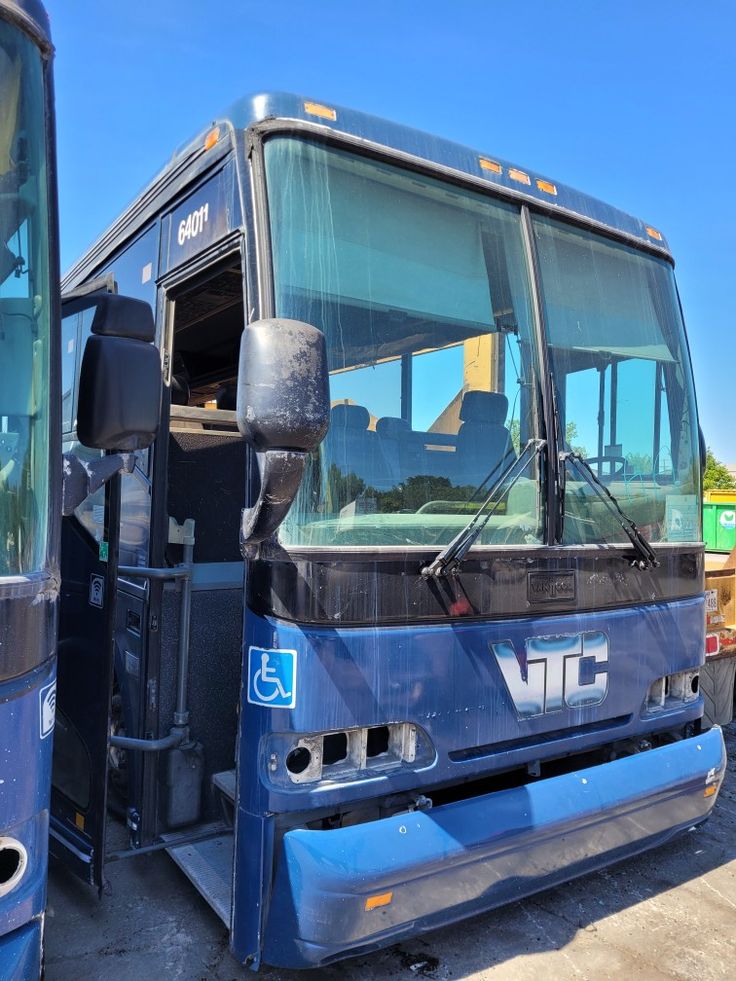 two buses parked next to each other in a parking lot with one door open and the other closed