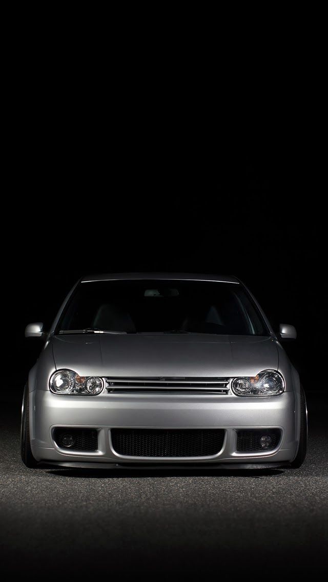 the front end of a silver car on a dark background