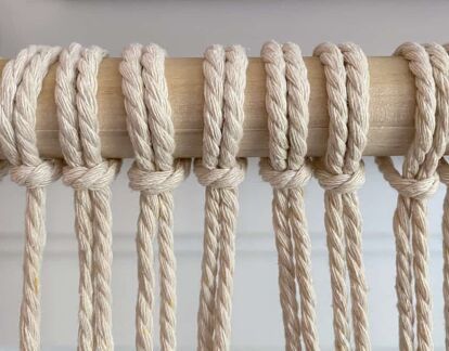 several ropes hanging from a wooden pole with some knots on it's end and one knot in the middle