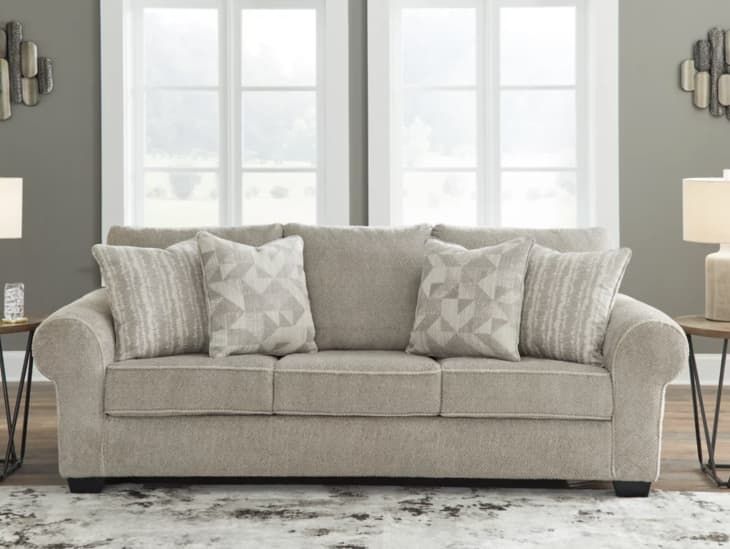 a living room scene with focus on the couch and two side tables in front of the window